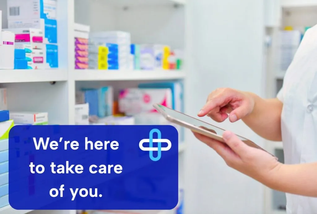 Here To Care An image of a person in a pharmacy near some shelves holding a tablet and interacting with it. An overlay says 'we're here to take care of you.'