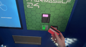 A hand holding a debit card in front of the contactless reader on the 24/7 collection point.
