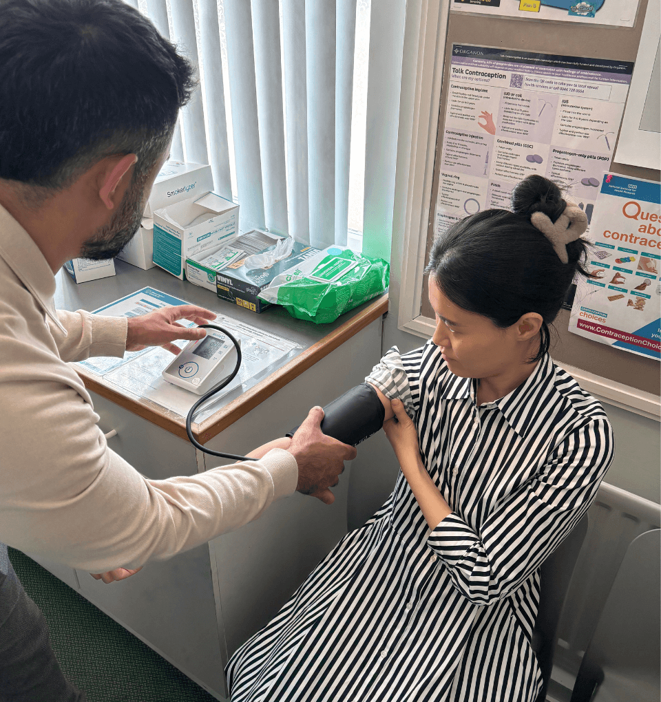 Our Pharmacist Faisal performing a blood pressure check on a patient in the consulting room.