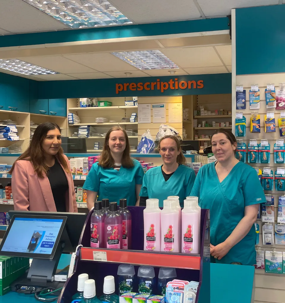 Members of the Ashington Pharmacy team smiling at the pharmacy counter.